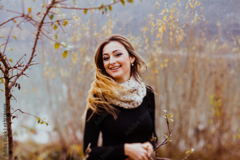 Lovely young woman wears knitted scarf and black dress, while walking in autumn park. Lovely young woman wears knitted scarf and black dress, while walking in autumn park.