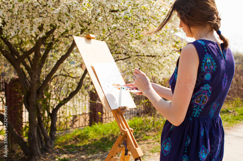 Canvas Print Artist paints a picture of blooming cherry tree in the garden.