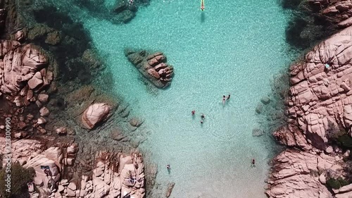 Drone video of beautiful Cala Coticcio, Sardinia, Italy. People swimming in crystal clear turquoise water.  photo