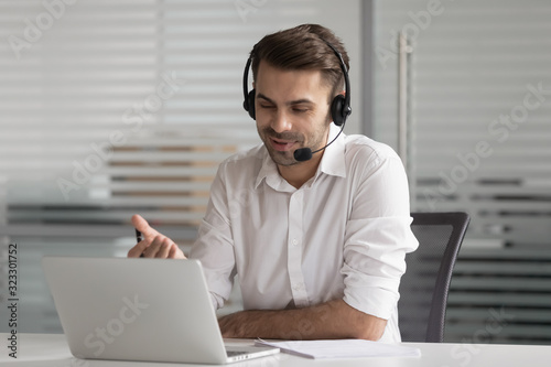 Smiling male worker in headset talking on video call photo