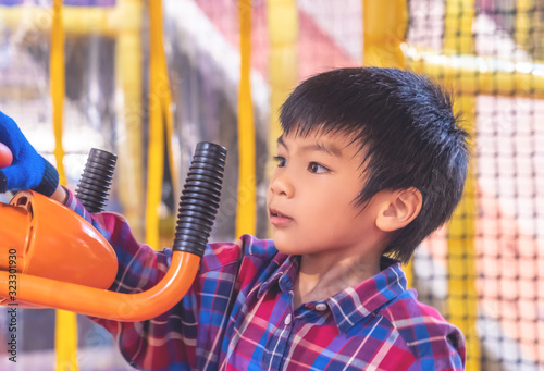 Littke asian kid is having fun playing with ball cannnon in Indoor playground photo