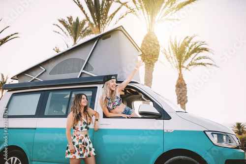 Two young women having fun in her van near the beach