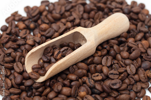 A wooden scoop on scattered coffee grains
