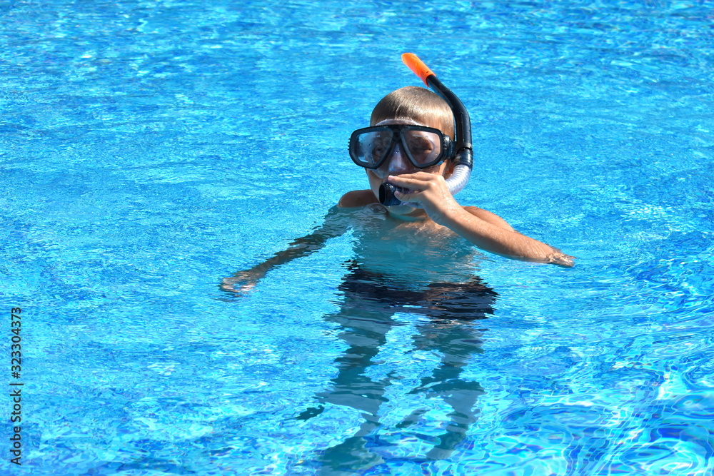 Baby boy in the water mask in the pool. Child swimmer in the water autdoor.