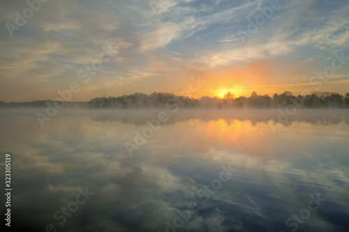 Landscape at sunrise of Whitford Lake in fog with mirrored reflections in calm water  Fort Custer State Park  Michigan  USA