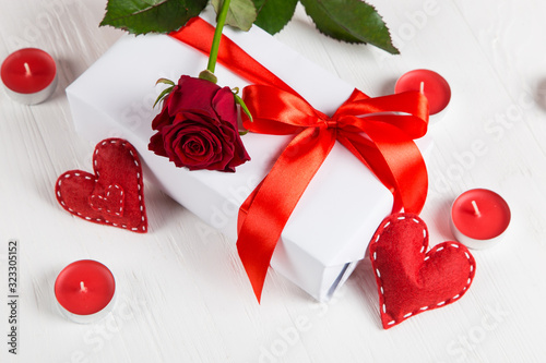 Gift with red ribbon, red rose and heart on a white background. The concept for Valentine's Day, a romantic gift to a loved one for the holiday.