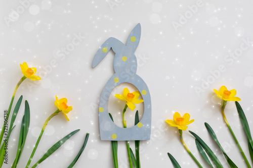 Composition of Easter bunny rabbit frame and yellow daffodil on beige background  flowerscape flat lay