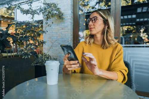 Mujer tomando café en starbucks con celular en mano samsung photo
