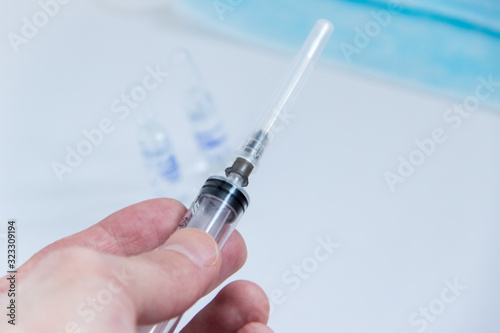 syringe with needle covered in mans hand close up image.