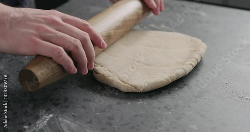 Slow motion man rolling dough on concretre countertop photo