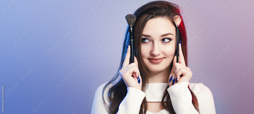 studio portrait of a cute girl with makeup brushes on head like horns, face of funny young woman, concept of female beauty and cosmetics studio portrait of a cute girl with makeup brushes on head like horns, face of funny young woman, concept of female beauty and cosmetics