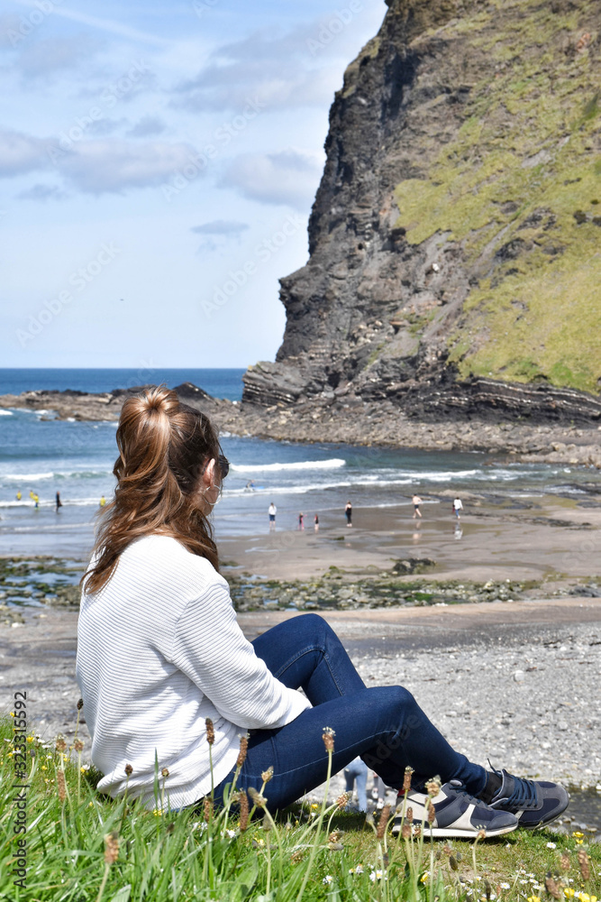 a woman sitting on her back looking at the beach