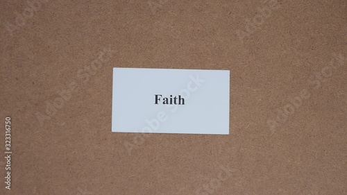 FAITH. Top shot - Hand puts paper card with word. CORE VALUE concept.