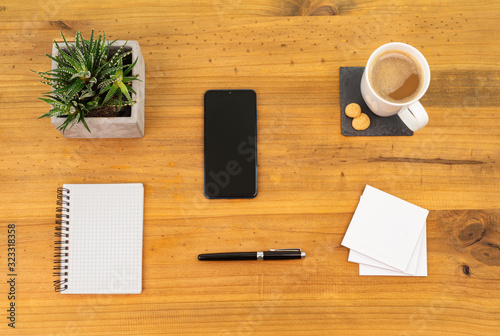Table Top desk view with pencil a plant, coffee, workspace, mobile display and laptop