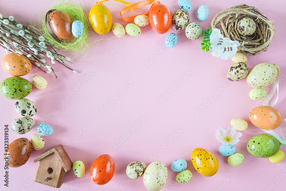 Fototapeta Beautiful easter holiday background. Frame of multicolored eggs, nest, birdhouse and willow twigs on pink background. Space for text