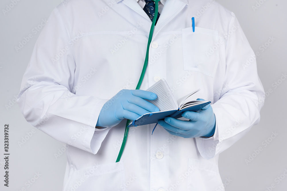 doctor in a white coat and blue gloves holds a blue paper notebook for notes doctor in a white coat and blue gloves holds a blue paper notebook for notes
