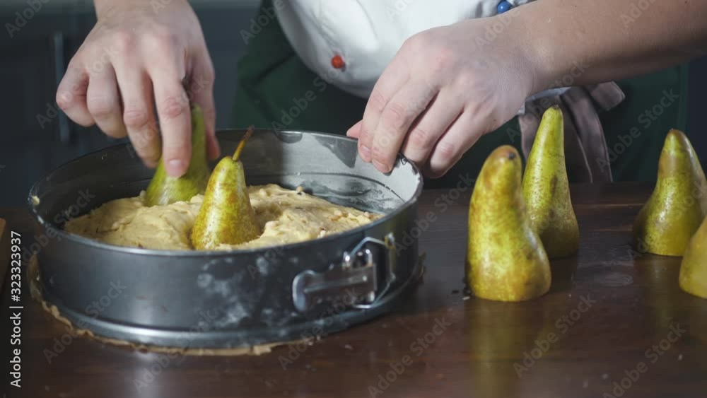 Baker puts pears in cake dough lying in a baking dish. Pie and bakery products. Bake food on cuisine. Healthy nutrition in gourmet kitchen. Making meal. Prepare food to eat. Delicious pastry dish. Baker puts pears in cake dough lying in a baking dish. Pie and bakery products. Bake food on cuisine. Healthy nutrition in gourmet kitchen. Making meal. Prepare food to eat. Delicious pastry dish.