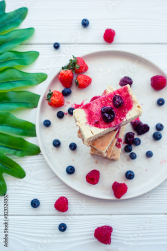 Slice of classic cheesecake with fresh berries on the white plate - healthy organic summer dessert.