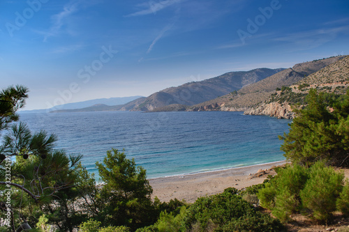 Seawater surface view horizon and the green pine trees with the mountains view on background, Greece paradise island Chios beach