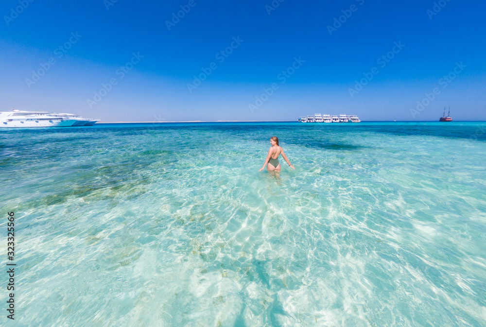 A girl in a green swimsuit to bathe in the blue water of the red sea. It's sunny outside A girl in a green swimsuit to bathe in the blue water of the red sea. It's sunny outside