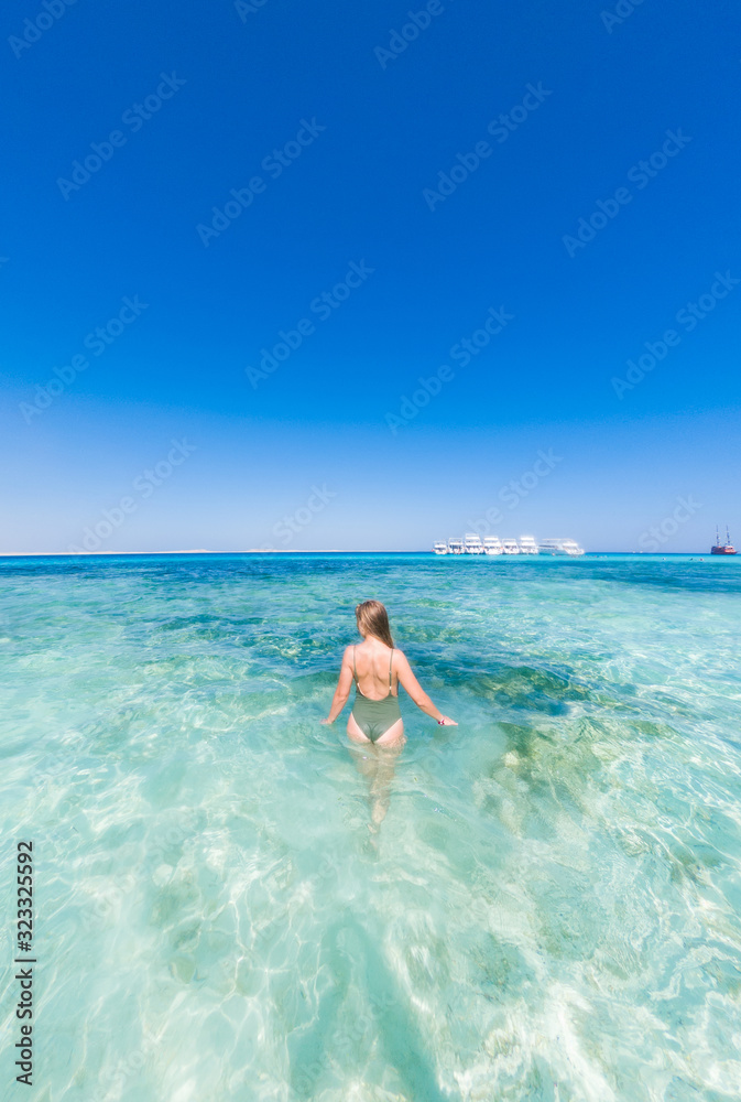 A girl in a green swimsuit to bathe in the blue water of the red sea. It's sunny outside A girl in a green swimsuit to bathe in the blue water of the red sea. It's sunny outside