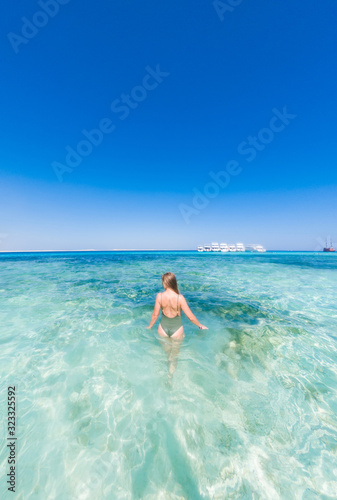 A girl in a green swimsuit to bathe in the blue water of the red sea. It s sunny outside