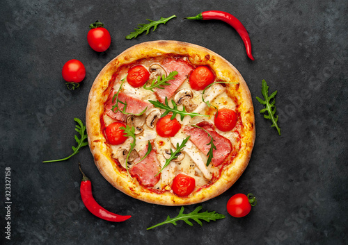  meat pizza with cheese, chicken, ham, champion mushrooms, tomatoes on a stone background
