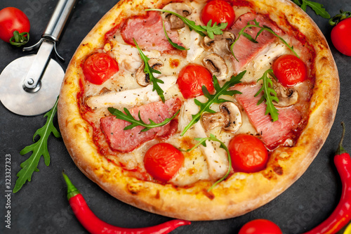  meat pizza with cheese, chicken, ham, mushrooms, tomatoes on a stone background