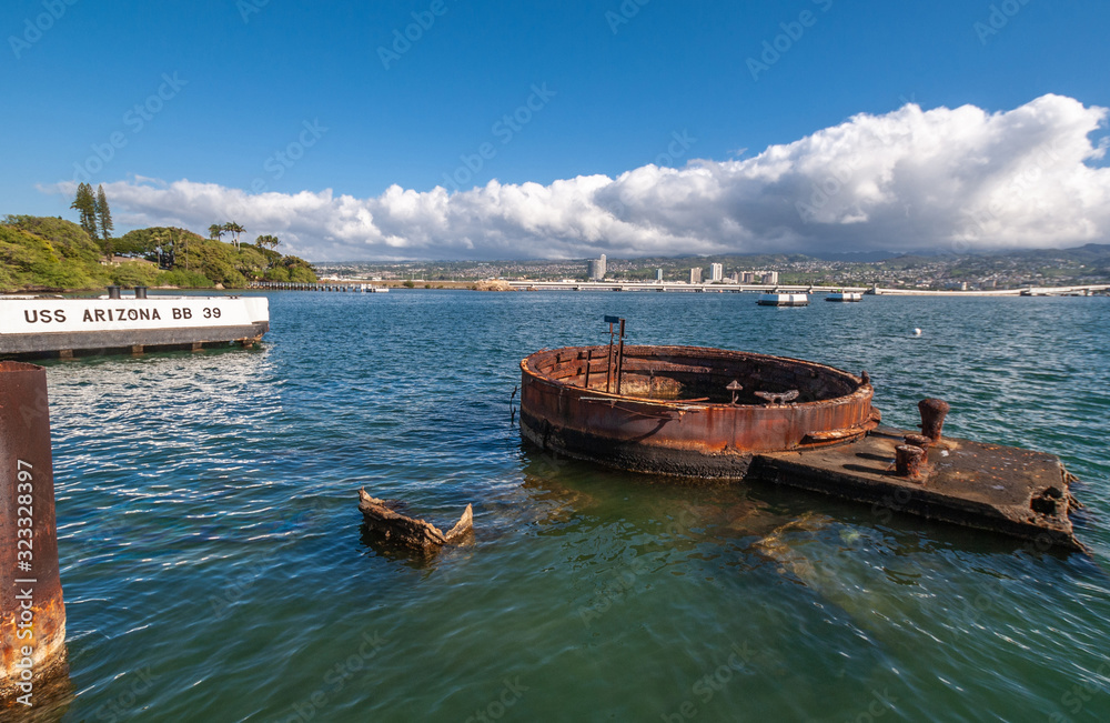 Oahu, Hawaii, USA. - January 10, 2012: Pearl Harbor. Rusty parts of USS Arizona sticks out of greenish sea water with Honolulu skyline in back under blue cloudy sky. Mooring block of shp in photo. Oahu, Hawaii, USA. - January 10, 2012: Pearl Harbor. Rusty parts of USS Arizona sticks out of greenish sea water with Honolulu skyline in back under blue cloudy sky. Mooring block of shp in photo.