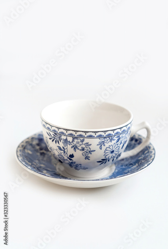 Ceramic saucers with a cup for tea in blue with flowers. New luxury elegance dinnerware on a isolated white background. Trendy plate. Flat lay view.