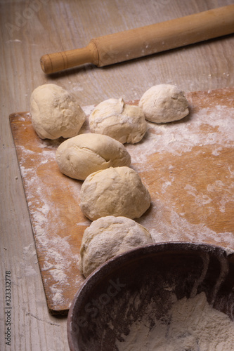 Balls of dough. Plywood cutting board, wooden flour sieve and wooden rolling pin - tools for making dough.