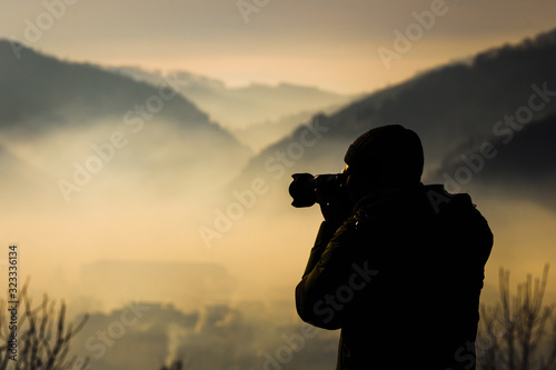 Photographer silhouette over misty morning landscape