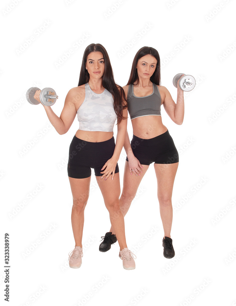 Two woman exercising with dumbbells in the studio Two woman exercising with dumbbells in the studio