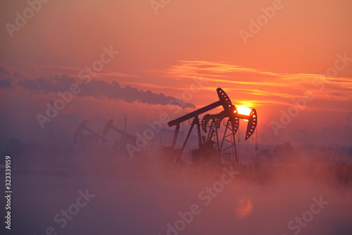 The oil pumping units by lakeside sunrise.