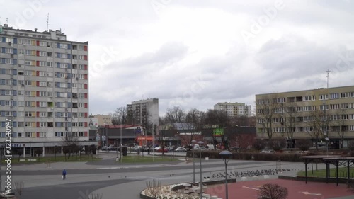 Flock of pigeons flying through small square in Poland. Birds in cold winter during day.