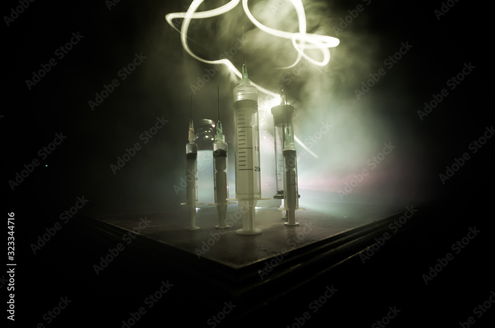 Fototapeta premium Medical syringe on wooden table with toned foggy background. Creative artwork decoration