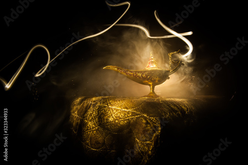 Lamp of wishes concept. Antique Aladdin arabian nights genie style oil lamp with soft light white smoke, Dark background.