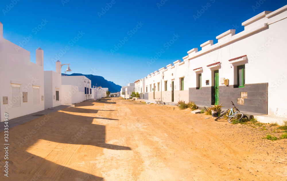 Typical street view from Caleta del Sebo, the main town of La Graciosa Island (Chinijo archipelago), very close to Lanzarote Island. Spanish white houses among volcanic landscape.