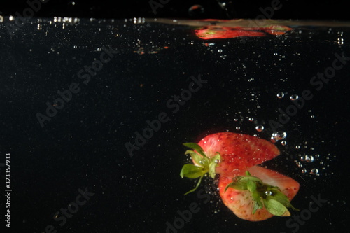 strawberry falling into the water in black background