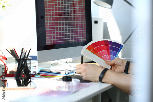 Male serviceman hold in hand fantail making colour test at worktable for further promotion closeup