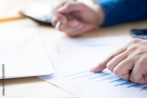 Businessman is pointing on the graph and inspecting the business reports graphs to audit the financial reports. Analyzing the revenue and auditing the budget concept.
