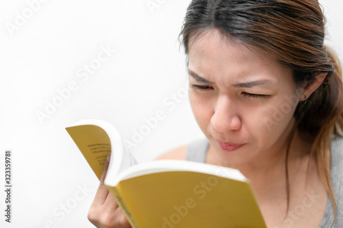 Asian woman reading book, has bad vision sight problems, selective focus, myopia and eyesight problem concept.