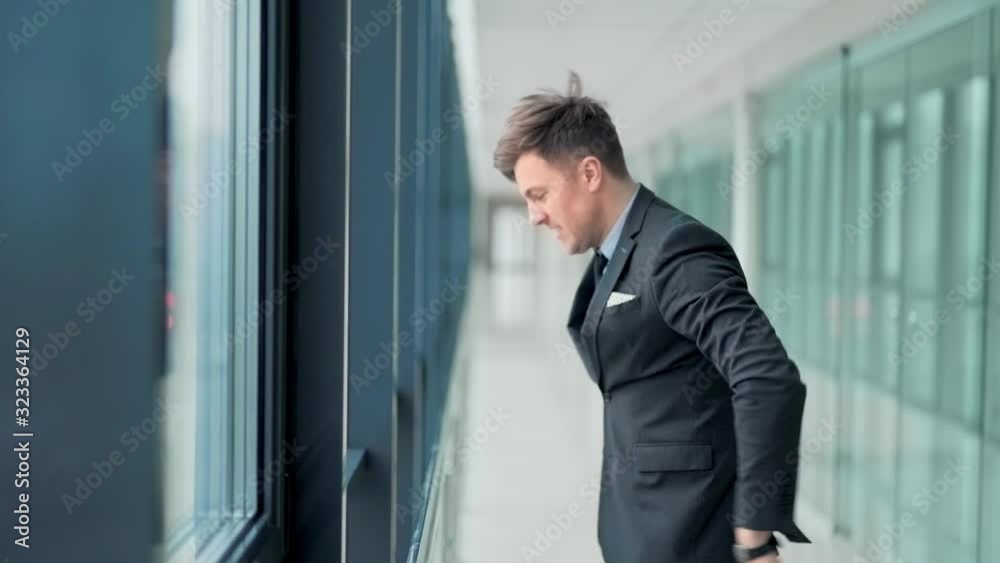 Closeup, handsome man in business suit standing at window aggressively knocking and angry
