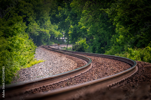 Empty Railroad track winding through the trees and vanishes into the horizon.