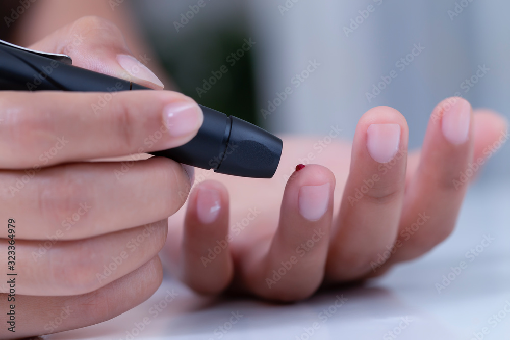 Female using lancelet on finger, Diabetic checking blood sugar levels. Female using lancelet on finger, Diabetic checking blood sugar levels.