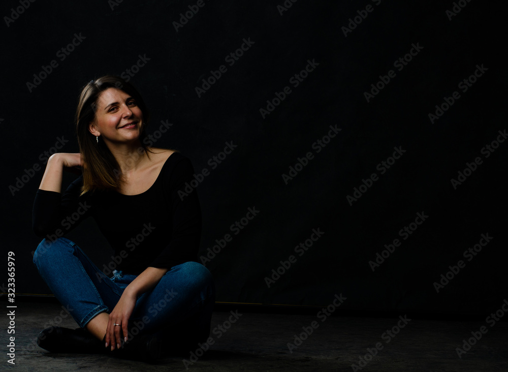 Young beautiful woman wearing in a black leather jacket, black top, short skirt and boots posing over black background. Studio shot of blonde woman against black background Young beautiful woman wearing in a black leather jacket, black top, short skirt and boots posing over black background. Studio shot of blonde woman against black background