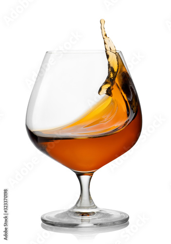 Fototapeta splash of brandy in snifter glass