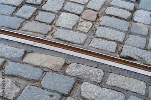 Close-up of a tram rail laid in a cobblestone pavement