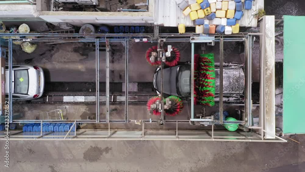 Car wash tunnel with single Car, brushes spinning and water sprinklers, Top down aerial view. Car wash tunnel with single Car, brushes spinning and water sprinklers, Top down aerial view.