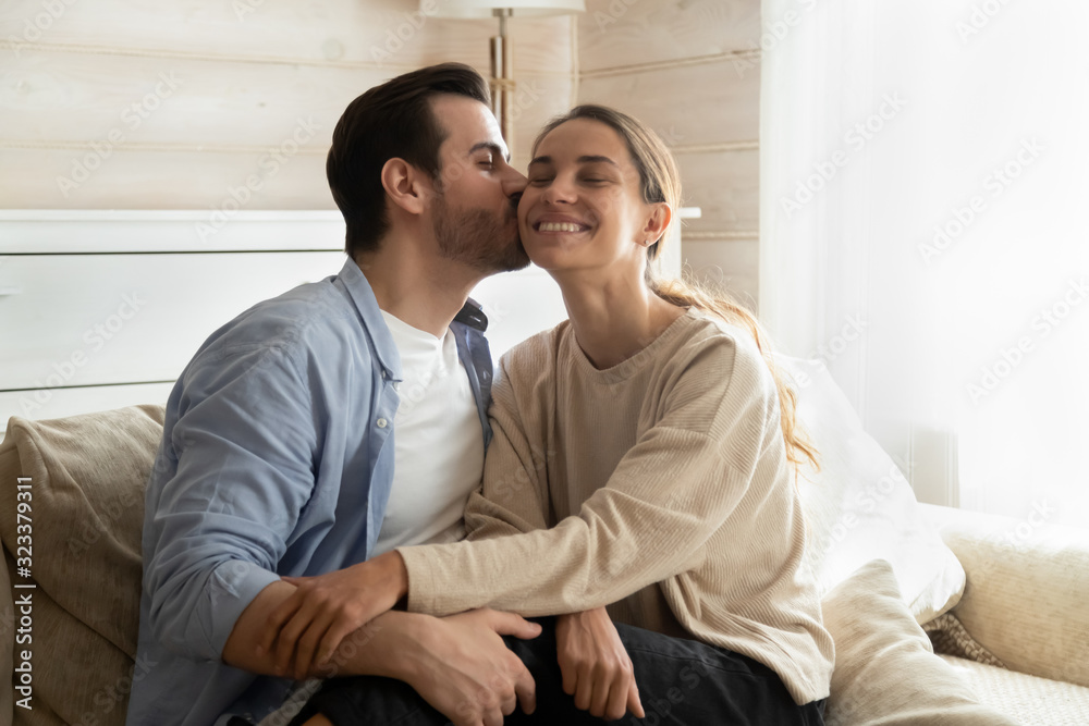 Loving man kiss girlfriend relaxing on couch together Loving man kiss girlfriend relaxing on couch together